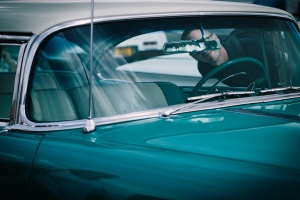 A man in Los Angeles, CA checking a classic blue used car which is for sale.